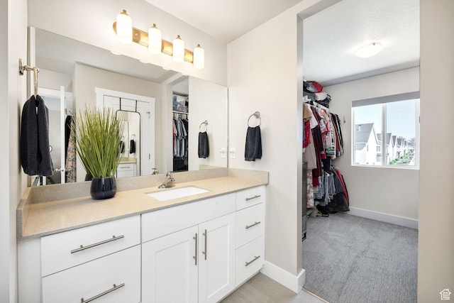 bathroom featuring baseboards, vanity, and a spacious closet