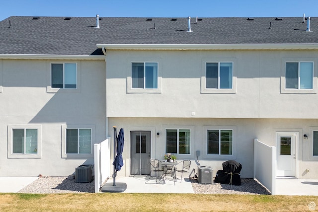 rear view of property featuring roof with shingles, a patio area, stucco siding, and cooling unit