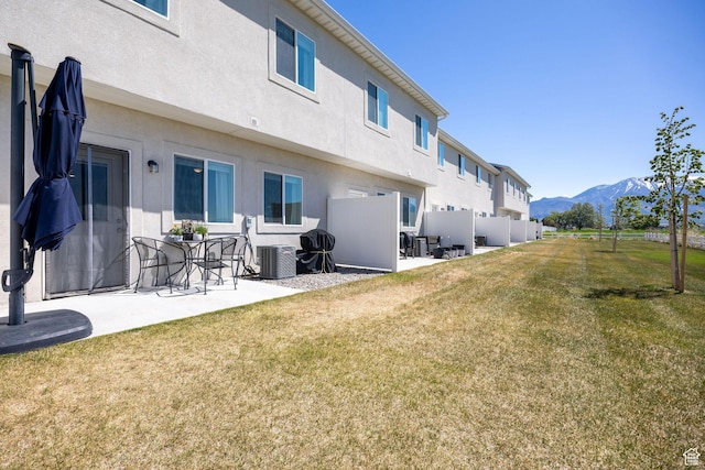 back of property featuring a mountain view, a patio area, stucco siding, and central air condition unit