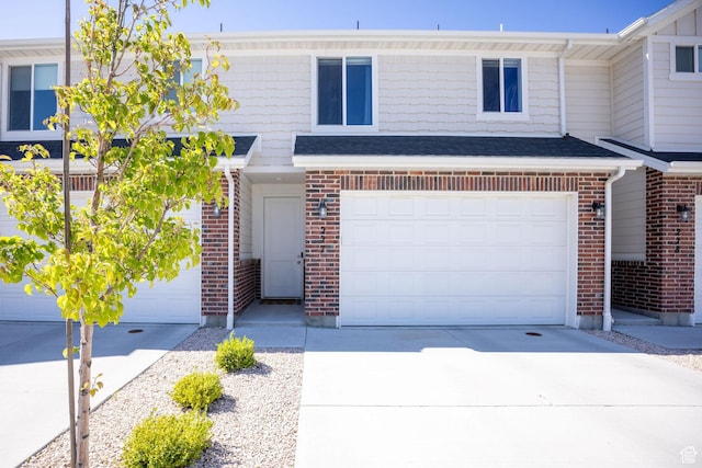 townhome / multi-family property featuring brick siding, concrete driveway, and a garage