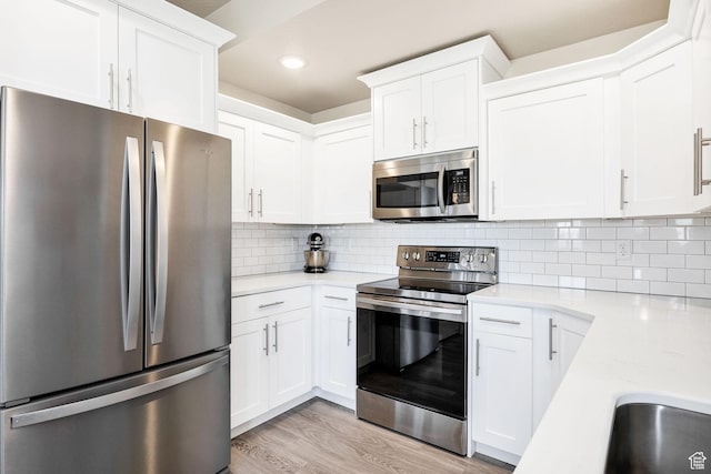 kitchen with stainless steel appliances, light countertops, white cabinetry, recessed lighting, and tasteful backsplash