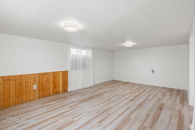 180 N 1100 E Unit 116, Washington, UT 84780 - unfurnished room featuring wood finished floors, wooden walls, a wainscoted wall, baseboards, and a textured ceiling
