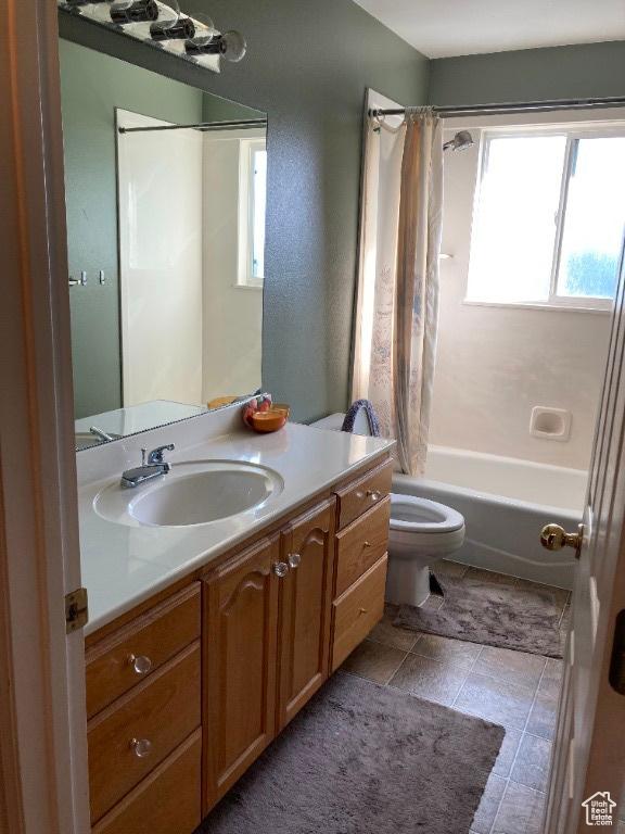 full bath with healthy amount of natural light, vanity, toilet, and shower / bathtub combination with curtain