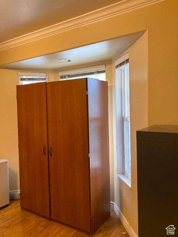 detailed view of wood finished floors, crown molding, and baseboards