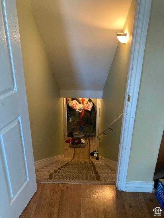 stairway with wood finished floors and lofted ceiling