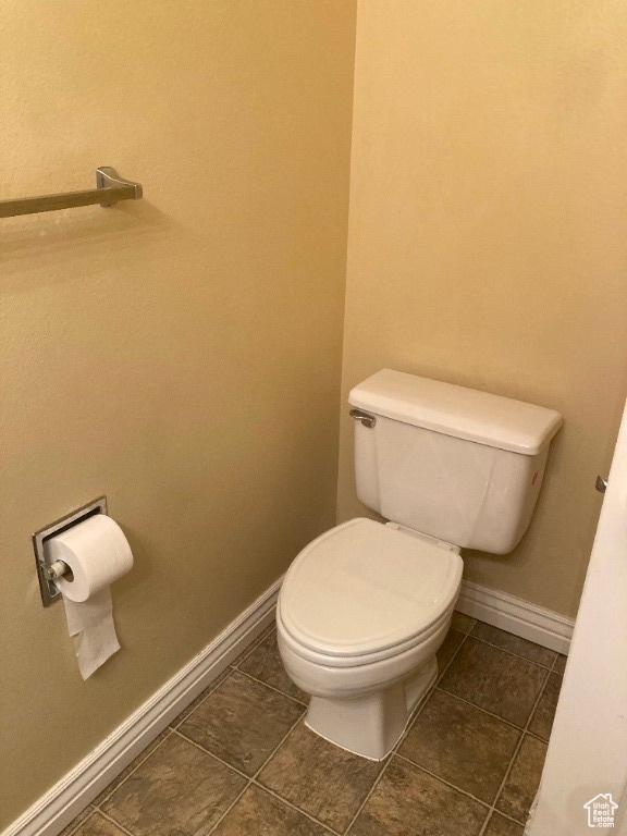 bathroom with toilet, baseboards, and tile patterned flooring
