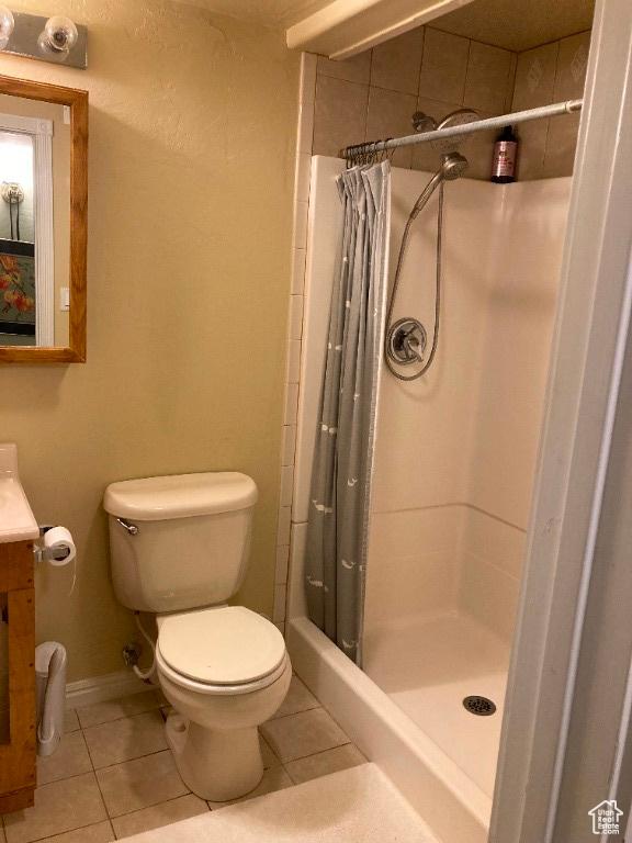 bathroom featuring tile patterned floors, a shower stall, toilet, vanity, and baseboards