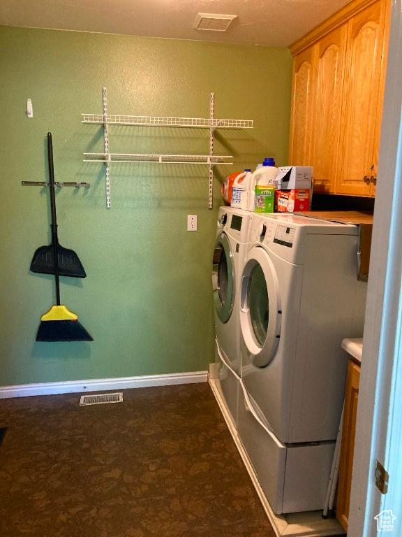 clothes washing area featuring cabinet space, independent washer and dryer, dark floors, and baseboards