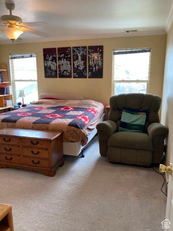 bedroom with ornamental molding, light colored carpet, and a ceiling fan