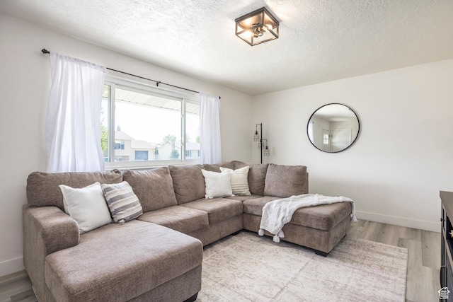 living room with a textured ceiling, light wood finished floors, and baseboards