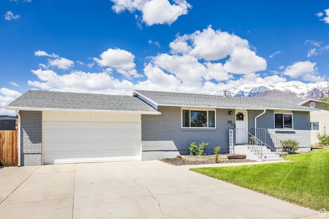 single story home with brick siding, a garage, concrete driveway, and a mountain view