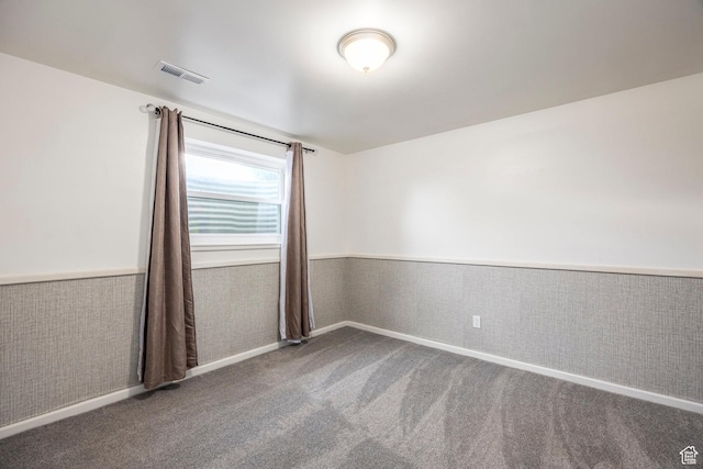 spare room with a wainscoted wall and carpet flooring