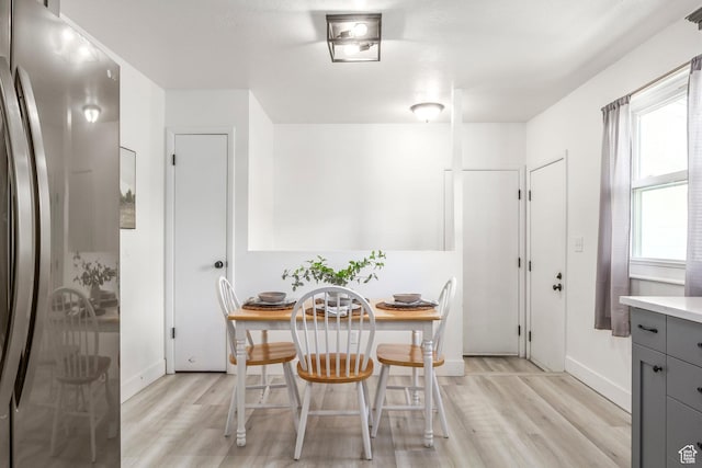 dining space featuring light wood-type flooring and baseboards
