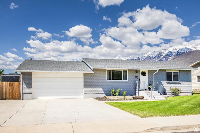 ranch-style home featuring brick siding, a garage, concrete driveway, and a mountain view