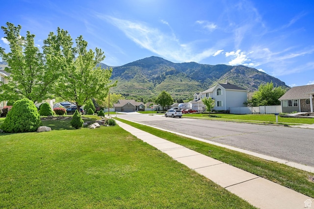 view of asphalt road with a residential view, a mountain view, sidewalks, and curbs