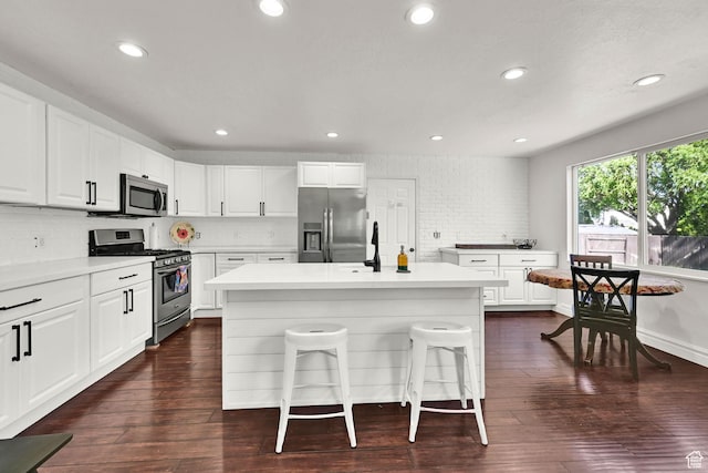 kitchen with appliances with stainless steel finishes, backsplash, a breakfast bar area, a center island, and recessed lighting