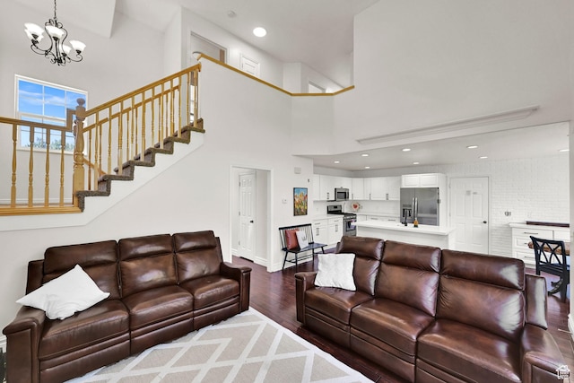 living area with wood finished floors, a chandelier, a high ceiling, stairway, and baseboards