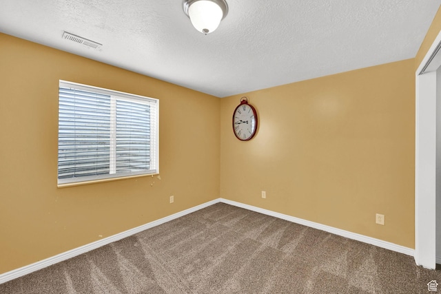 spare room with dark carpet, a textured ceiling, and baseboards