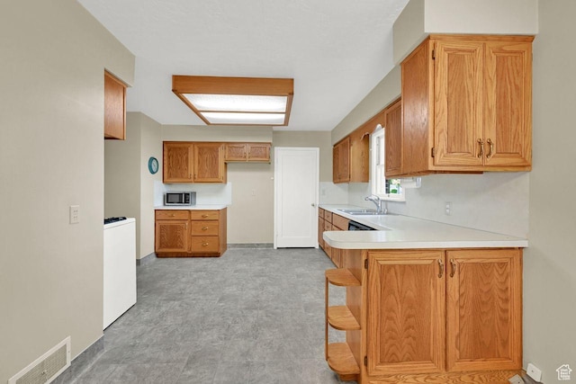 1375 E 3100th St S, Ogden, UT 84403 - kitchen with stainless steel microwave, a sink, light countertops, a peninsula, and brown cabinetry