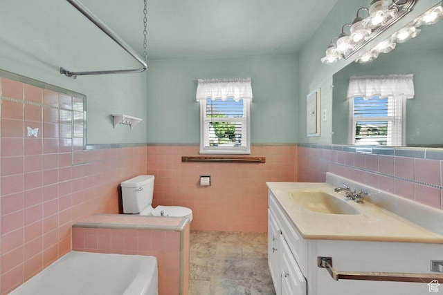 1375 E 3100th St S, Ogden, UT 84403 - bathroom with tile walls, a tub to relax in, a wainscoted wall, vanity, and toilet
