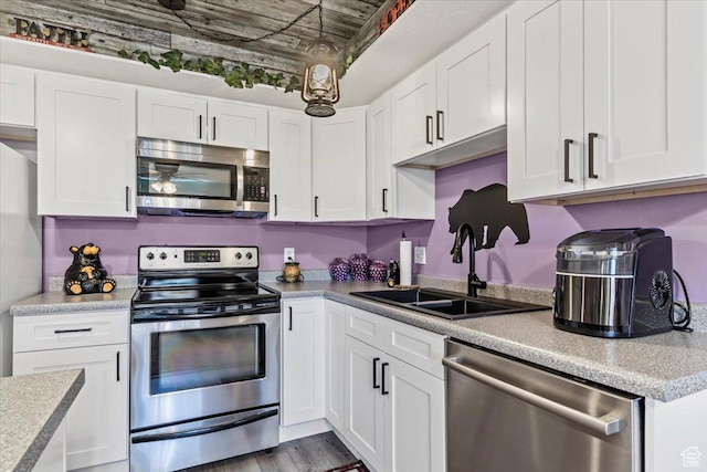 kitchen featuring stainless steel appliances, a sink, white cabinets, and light countertops