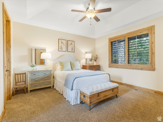 carpeted bedroom with a tray ceiling, baseboards, and a ceiling fan