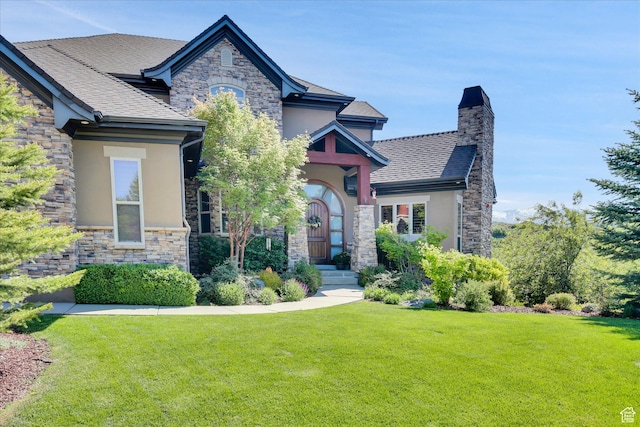 view of front of property featuring stone siding, stucco siding, and a front lawn