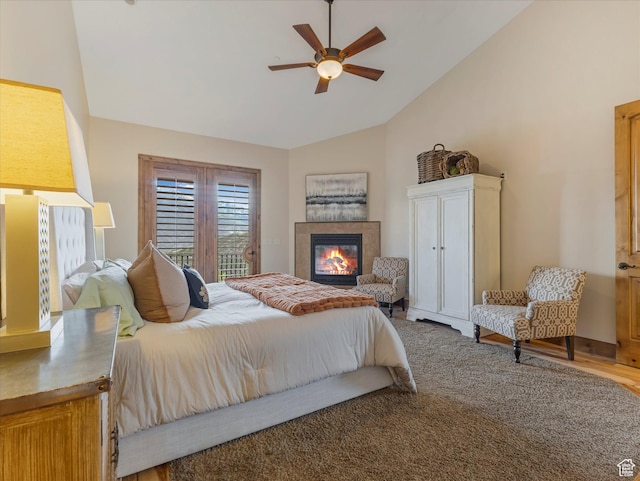 bedroom featuring vaulted ceiling, access to outside, a fireplace, wood finished floors, and ceiling fan