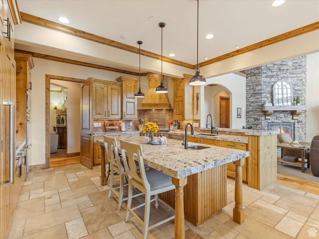 kitchen featuring stone tile flooring, a breakfast bar, custom range hood, backsplash, and recessed lighting