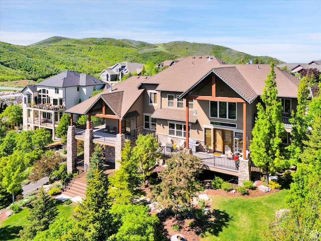 rear view of house featuring stucco siding, stone siding, a mountain view, a residential view, and stairway