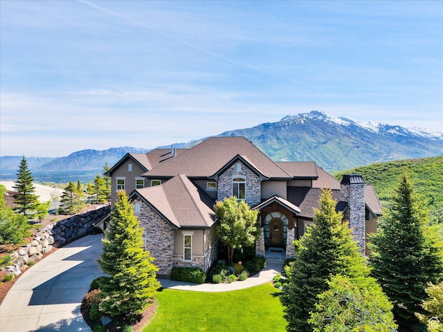 view of front of house with stone siding, stucco siding, a mountain view, and a front yard