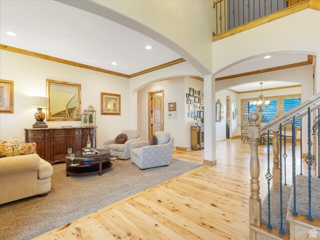 living area with arched walkways, wood finished floors, a chandelier, ornamental molding, and recessed lighting