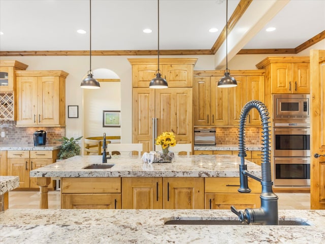 kitchen with ornamental molding, a sink, tasteful backsplash, stainless steel appliances, and light stone countertops