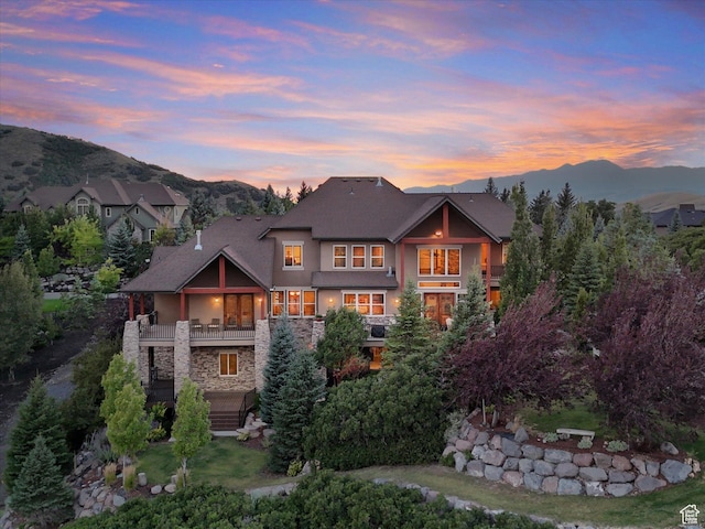view of front of home featuring stucco siding, a balcony, stone siding, and a mountain view