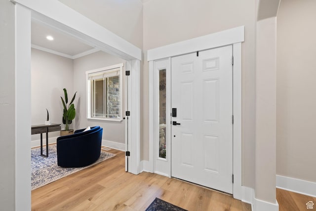 entrance foyer featuring wood finished floors, ornamental molding, and baseboards