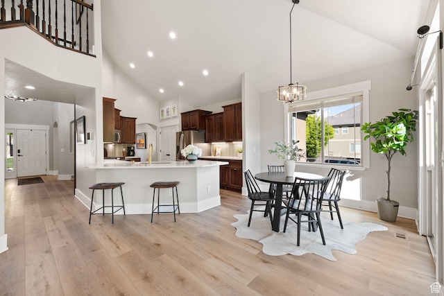 kitchen featuring stainless steel appliances, a chandelier, a breakfast bar, light wood finished floors, and a peninsula