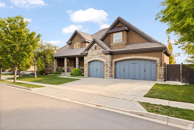 view of front of home featuring stone siding, stucco siding, driveway, covered porch, and a tile roof