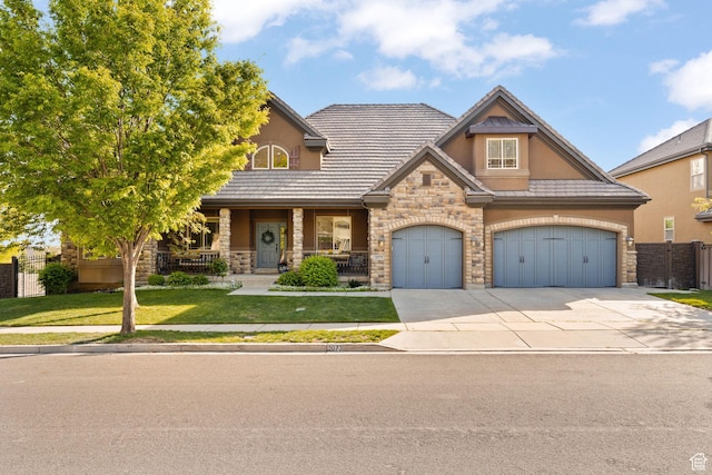 view of front of property featuring stone siding, stucco siding, a porch, driveway, and a tiled roof