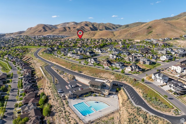 view of property location with a pool area, a mountain backdrop, and nearby suburban area