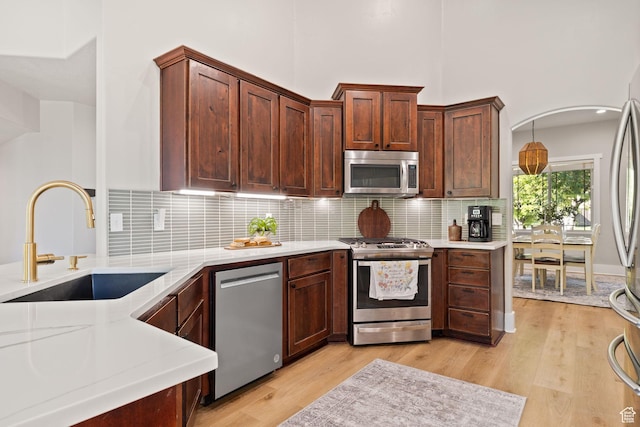 kitchen with stainless steel appliances, a sink, light countertops, and a high ceiling