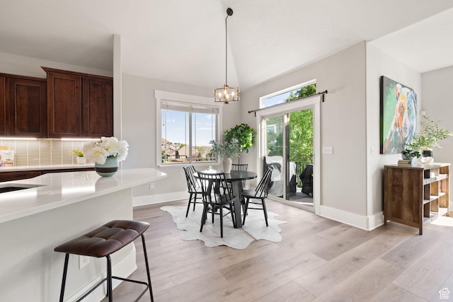 dining room featuring baseboards, light wood-style floors, and a chandelier