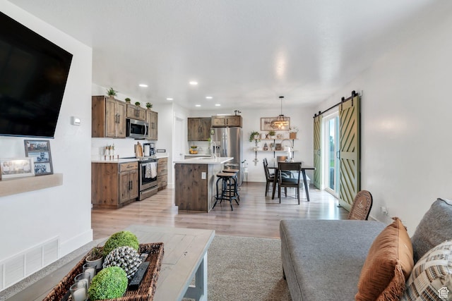 living area featuring light wood-style flooring, a barn door, and recessed lighting