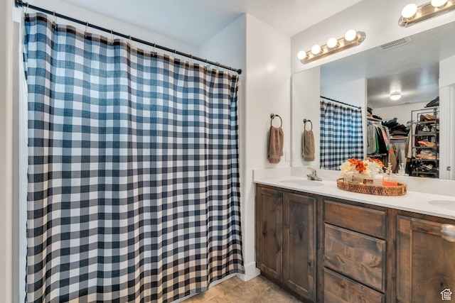 bathroom featuring double vanity, a walk in closet, and a shower with curtain