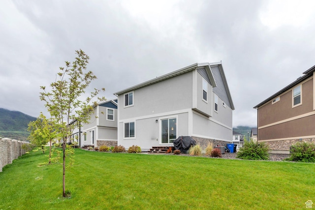 rear view of property featuring stone siding, stucco siding, and a lawn