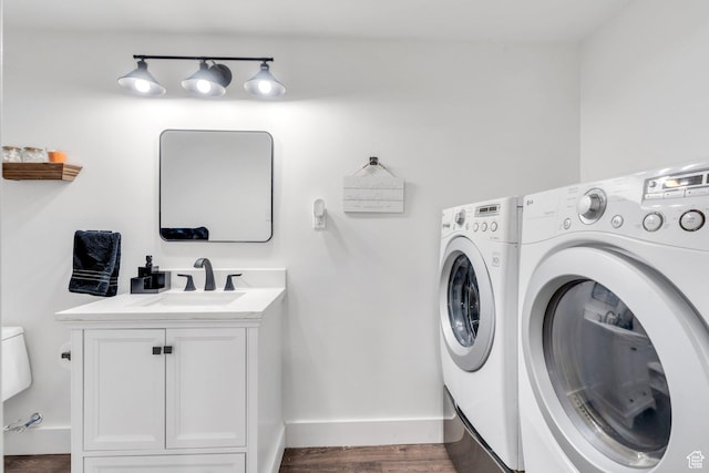 clothes washing area with washer and clothes dryer, baseboards, wood finished floors, and cabinet space