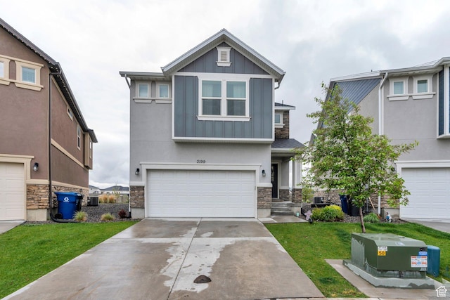 view of front of house featuring board and batten siding, stone siding, a garage, driveway, and a front lawn