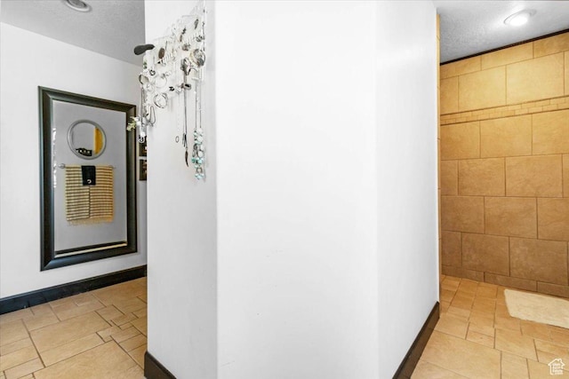 corridor with a textured ceiling and baseboards