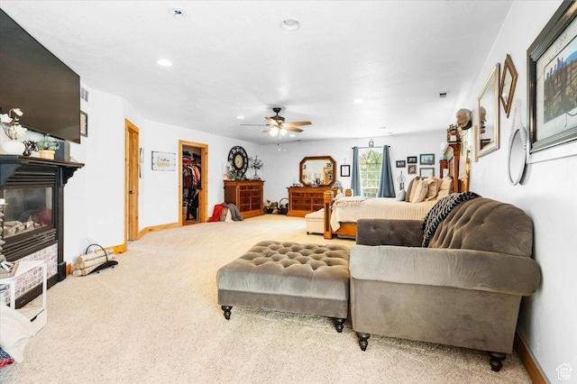 carpeted living room with a glass covered fireplace, a ceiling fan, baseboards, and recessed lighting