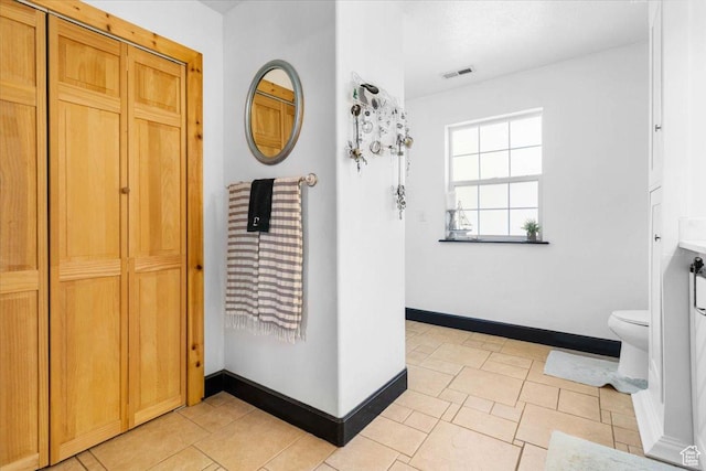 bathroom with toilet, baseboards, and a closet