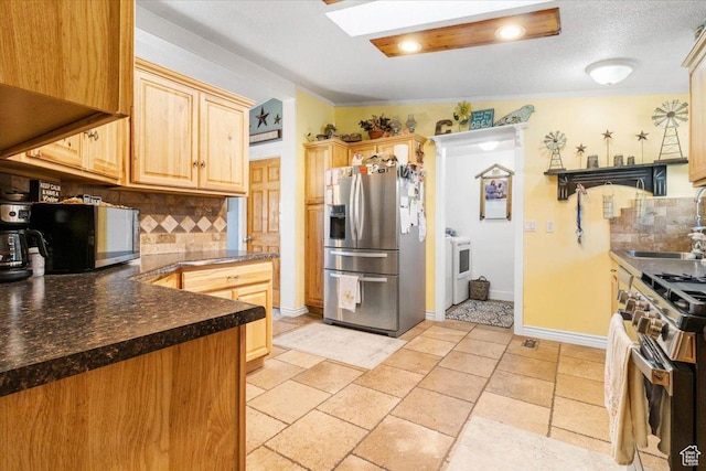 kitchen with stainless steel appliances, a sink, decorative backsplash, washer / dryer, and ornamental molding
